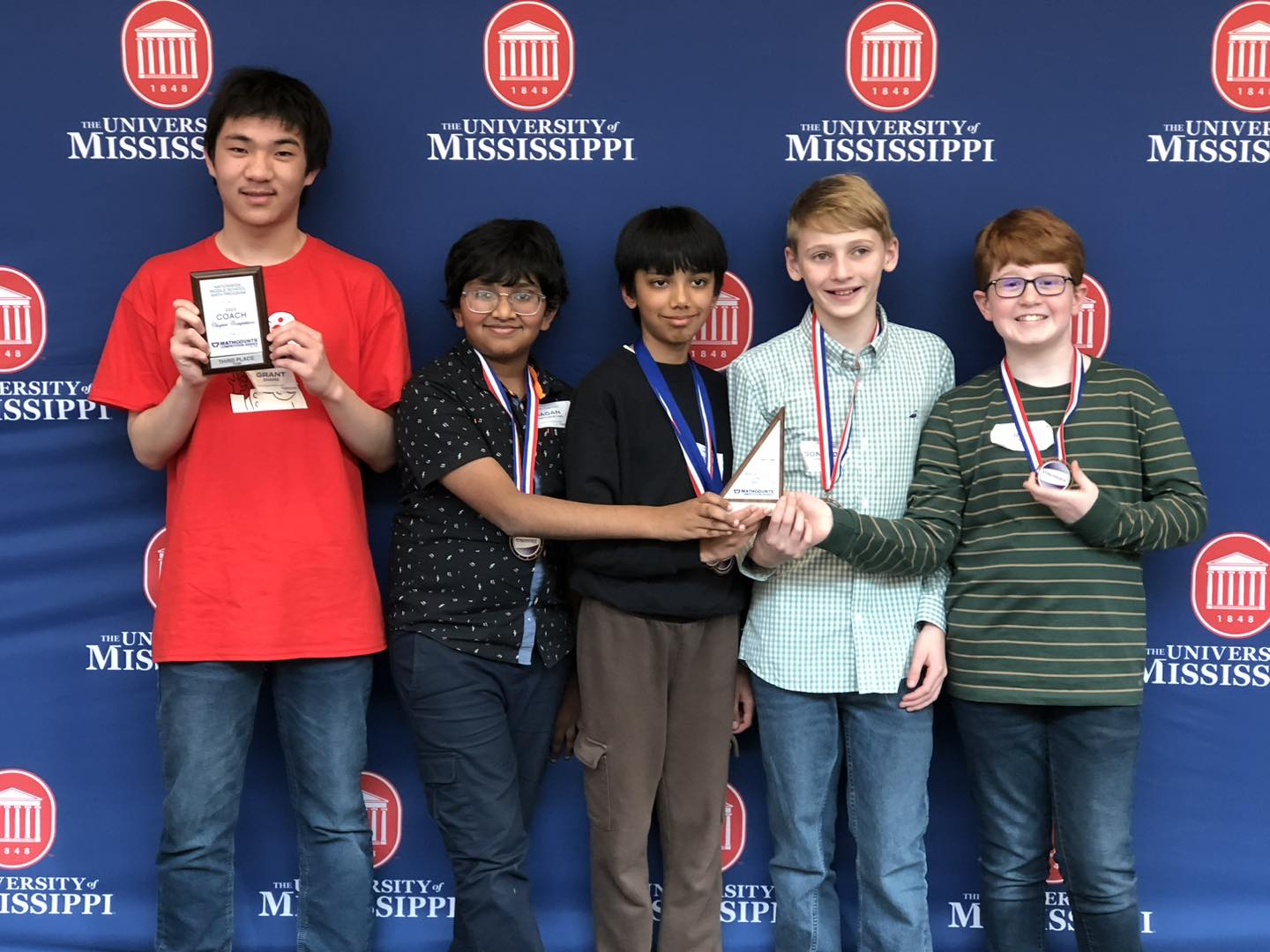 Cohort member Grant Zhang holds a MATHCOUNTS trophy with the team he coached.